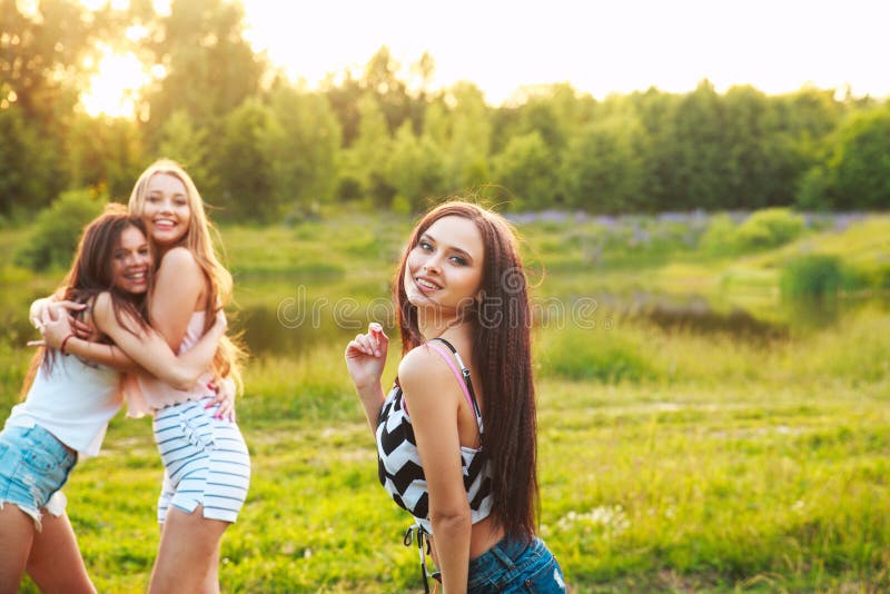 Three Beautiful Girls Walking And Laughing On Sunset In The Park