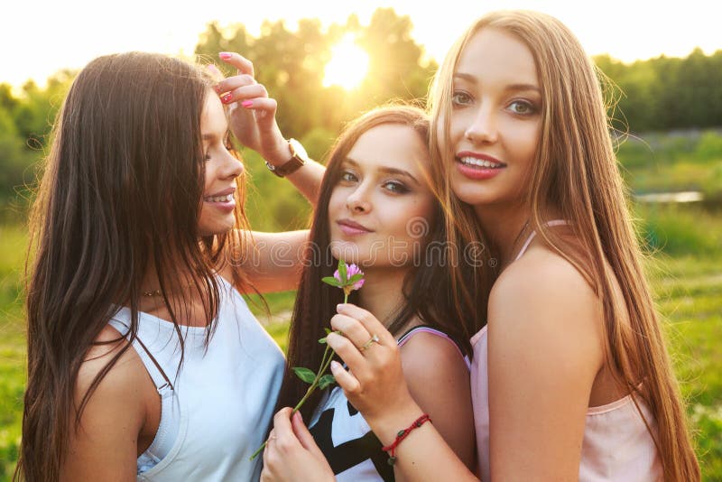 Three Beautiful Girls Walking And Laughing On Sunset In The Park