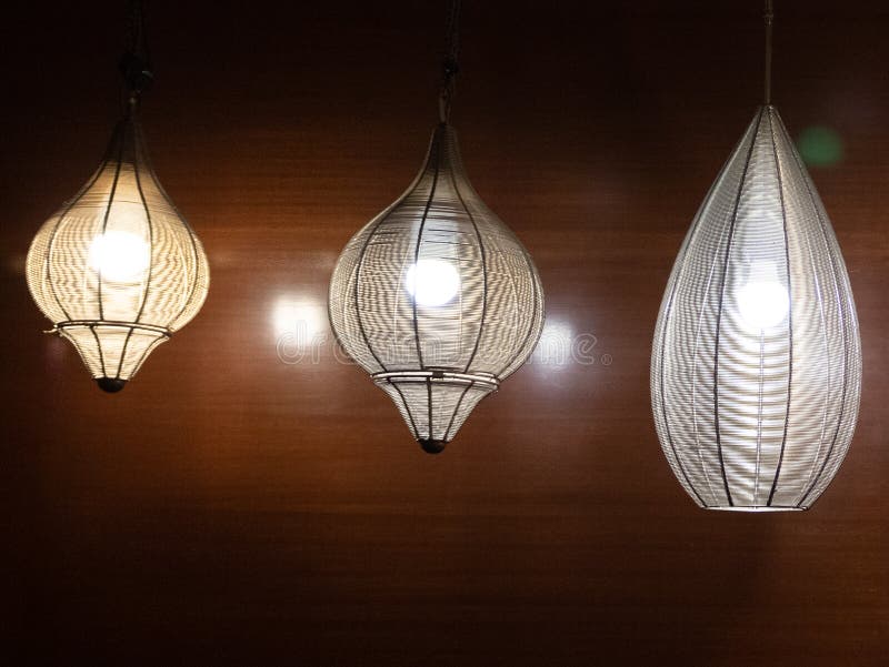 Three Beautiful Hanging Lights Glowing Bright and Brown Wooden Wall