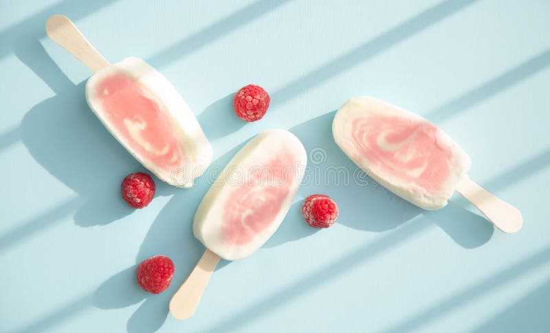 Three berry sorbet and yogurt popsicle with raspberry on a pale blue background. Three berry sorbet and yogurt popsicle with raspberry on a pale blue background