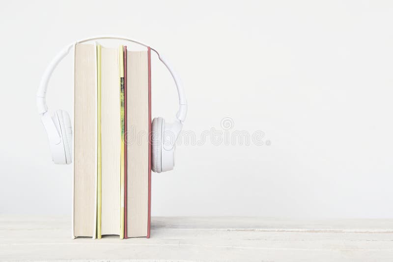Three books and hearphones on a wooden shelf against a white background. Reading concept and study metaphor with empty copy space for Editor`s text.