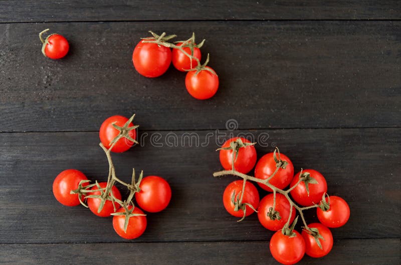 Three branches of red cherry tomatoes isolated on black wooden background royalty free stock images Three branches of red cherry tomatoes isolated on black wooden background royalty free stock images