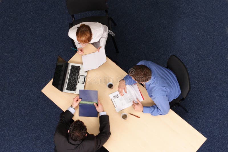 Businesspeople gathered around a table for a meeting, brainstorming. Aerial shot taken from directly above the table. Businesspeople gathered around a table for a meeting, brainstorming. Aerial shot taken from directly above the table.