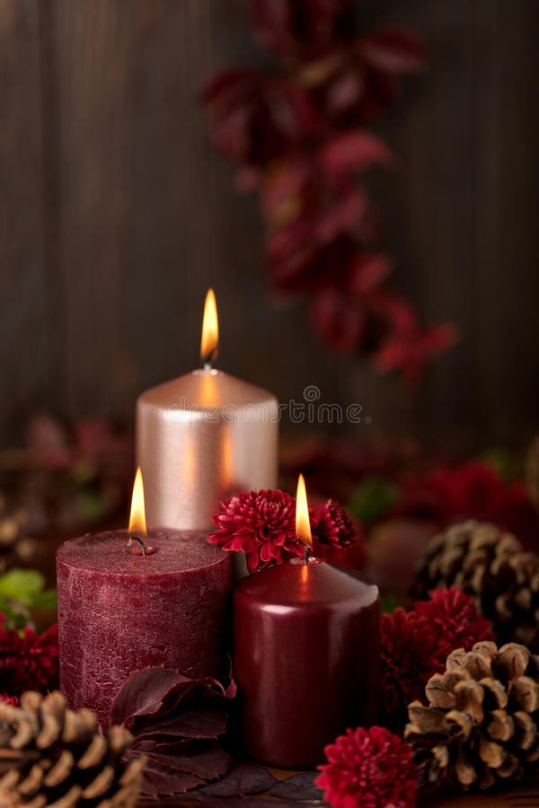 Three candles of crimson and pink color on a dark background wit