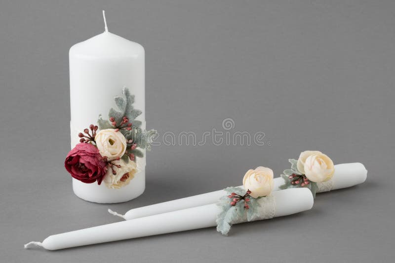 Three candles decorated with flowers on gray background stock photos