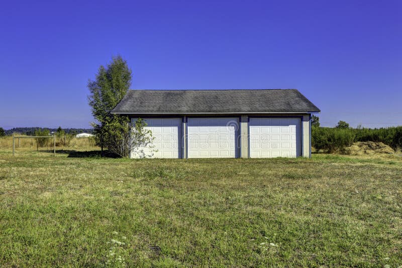 Three car garage with tile roof. Countryside landscape