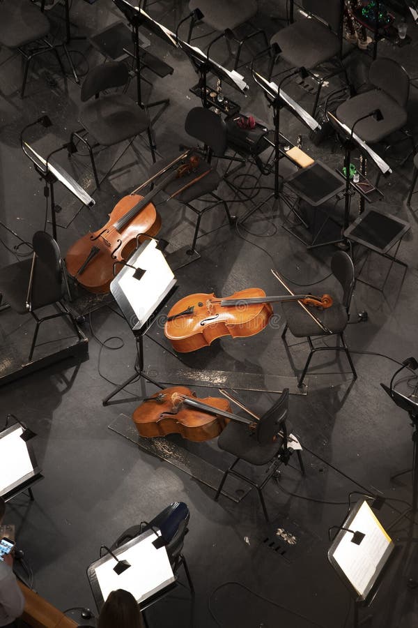 Three Cellos in the Orchestra Pit among the Chairs and Sheet Music
