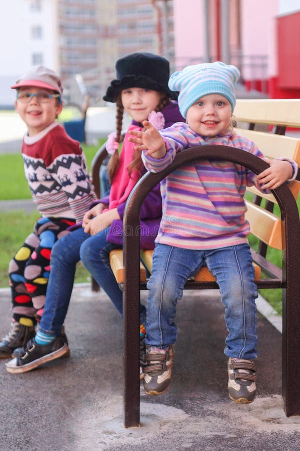 Three Children in Bright Clothes Sitting on a Bench Stock Photo Image