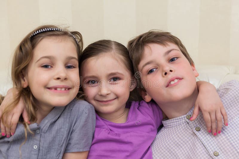 Three children sitting on the couch hugging