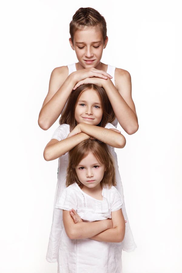 Three children in the studio on a white background, a brother and two sisters, put their hands on each other `s head, stand the t stock photography Three children in the studio on a white background, a brother and two sisters, put their hands on each other `s head, stand the t stock photography