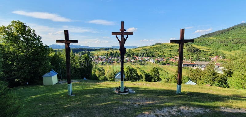 Three Christian wooden crosses in front of a village in the natural landscape in the foothills of the High Tatras in the north of