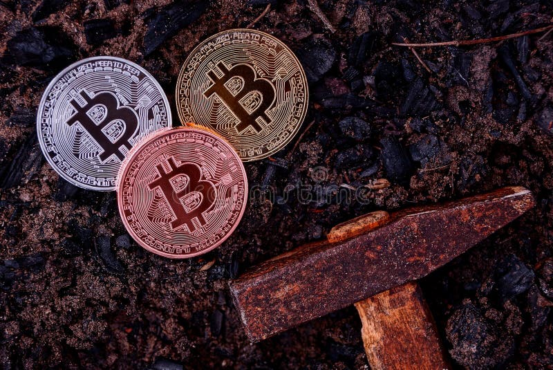 Three coins of bitcoin on black earth and a hammer royalty free stock photo Three coins of bitcoin on black earth and a hammer royalty free stock photo