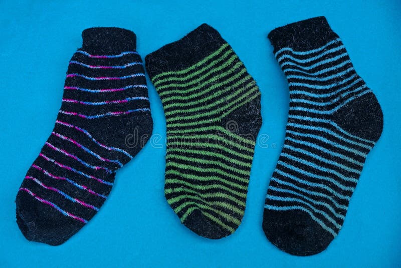 Three colored striped woolen socks on a blue table royalty free stock image Three colored striped woolen socks on a blue table royalty free stock image