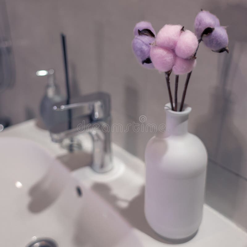 Three Cotton Flowers in a White Vase in the Bathroom Stock Photo