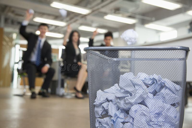 Three coworkers preparing to throw paper into waste basket royalty free stock photos Three coworkers preparing to throw paper into waste basket royalty free stock photos