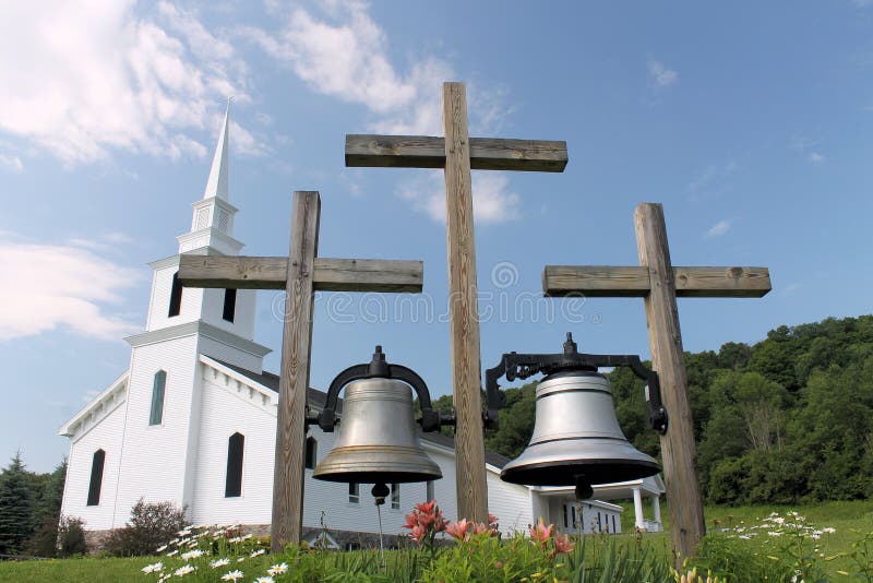 Two large bells hanging from three wooden crosses in front of a newly restored historic church in Morrisville, New York. Two large bells hanging from three wooden crosses in front of a newly restored historic church in Morrisville, New York