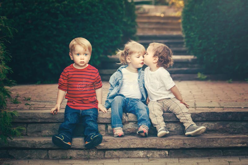 Three cute funny adorable white Caucasian children toddlers boys girl sitting together kissing each other royalty free stock photos Three cute funny adorable white Caucasian children toddlers boys girl sitting together kissing each other royalty free stock photos