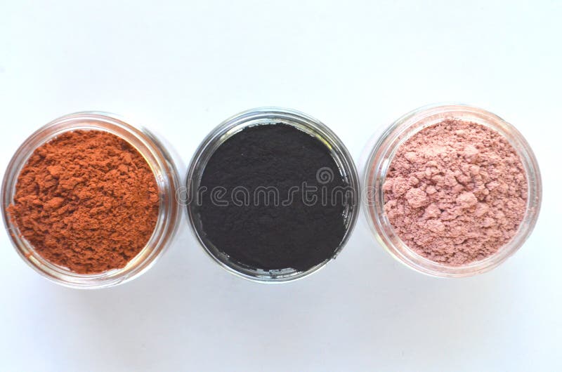 Three different mineral clays for facial masks - pink clay, red clay and activated charcoal in glass jars top view on white royalty free stock photos