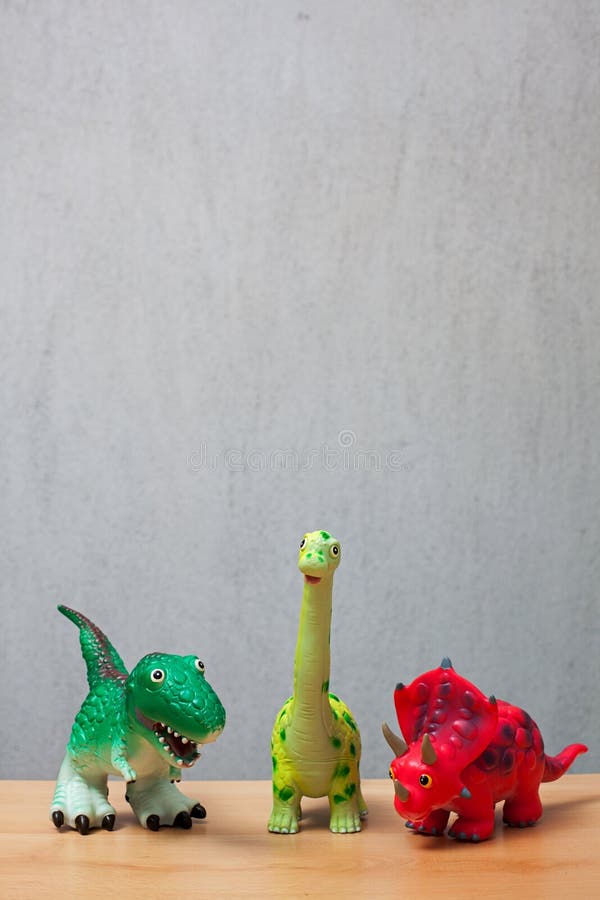 Three dinosaurs toys standing on a wooden floor. royalty free stock image Three dinosaurs toys standing on a wooden floor. royalty free stock image