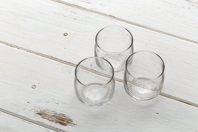 Three empty glasses on a white wooden table stock photo