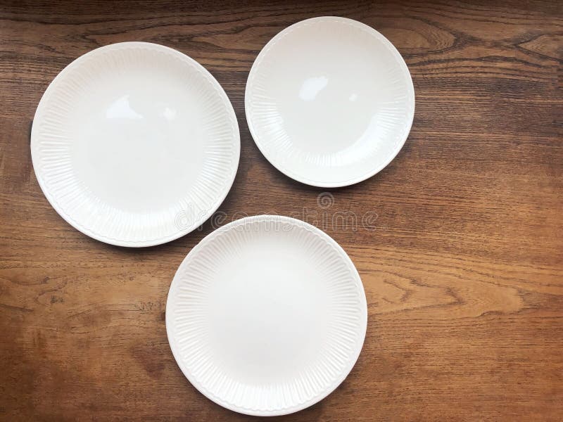 Three Empty White Plates on Wooden Table Top View. Copy Space Stock