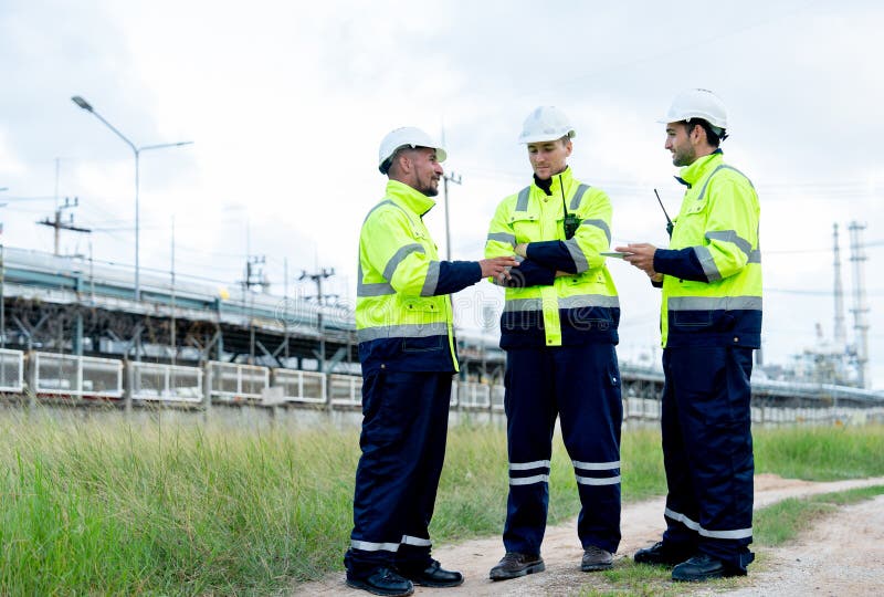 Three engineer or technician workers stand on the road near petrochemical factory and use tablet to discuss their work royalty free stock photography