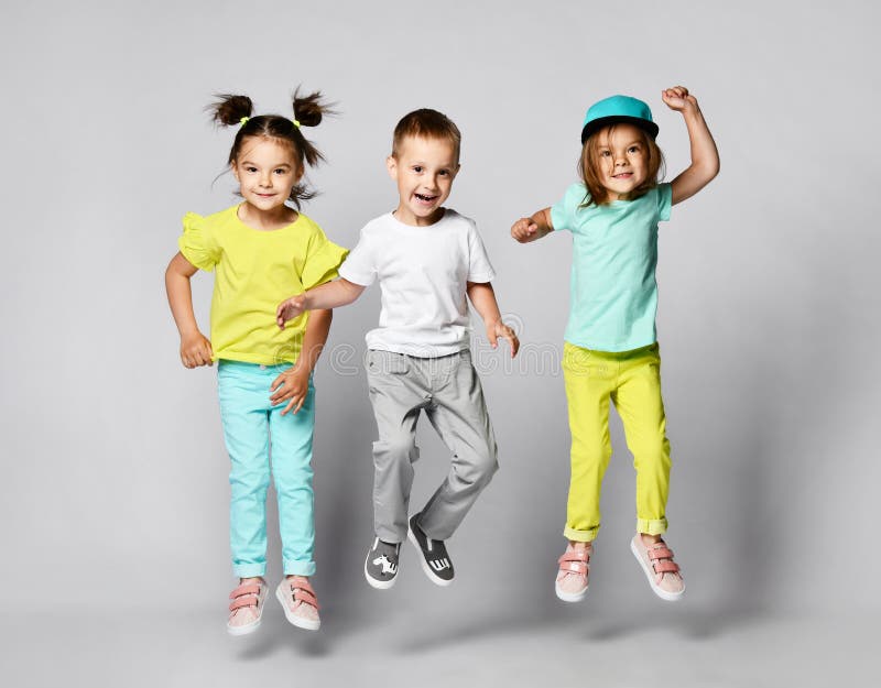 Three excited kids in fashion outfits, jumping over the light background. Two sisters and brother, friends in fashionable clothes royalty free stock photography Three excited kids in fashion outfits, jumping over the light background. Two sisters and brother, friends in fashionable clothes royalty free stock photography