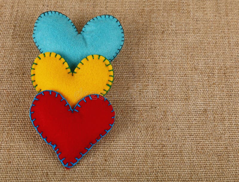 Three felt craft hearts, yellow, red and blue