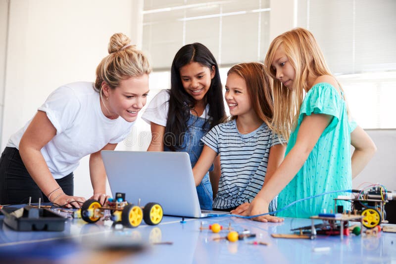 Three Female Students With Teacher Building Robot Vehicle In After School Computer Coding Class stock image