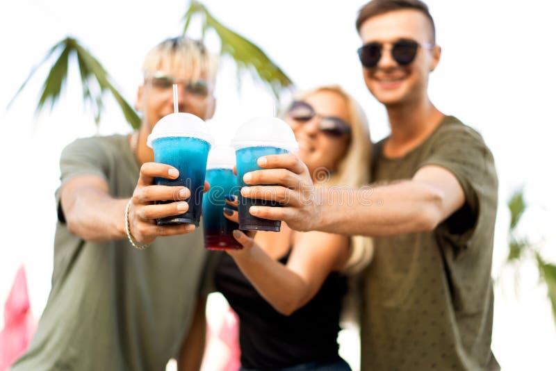 three friends cheerful company rest on a tropical beach and drink cocktails, very, magazine concept stock photography three friends cheerful company rest on a tropical beach and drink cocktails, very, magazine concept stock photography