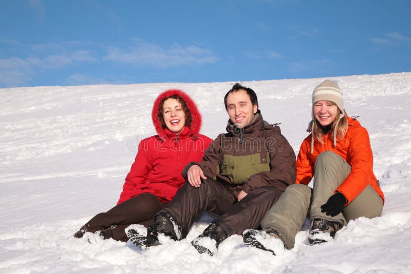 Three friends sit on snow