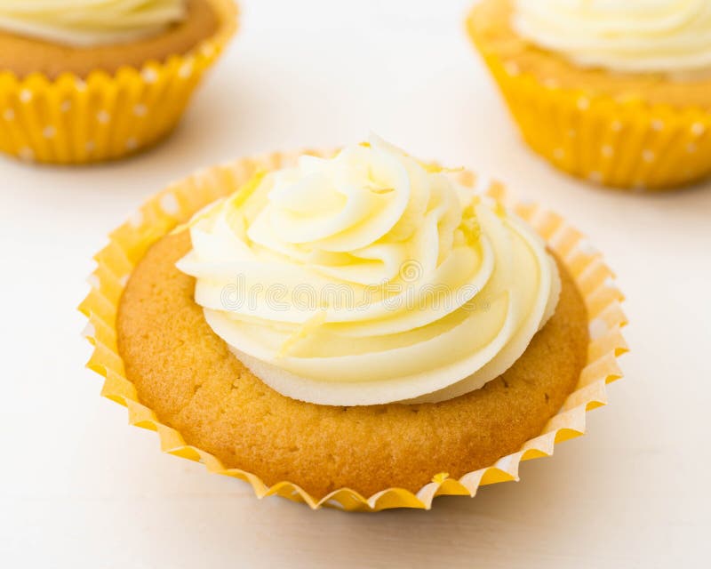 Three frosted cupcakes one in selective focus at the front. Close up looking down on a pretty frosted cupcake with two further cakes partially seen in the royalty free stock photo Three frosted cupcakes one in selective focus at the front. Close up looking down on a pretty frosted cupcake with two further cakes partially seen in the royalty free stock photo