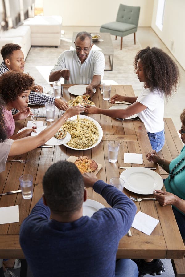 Three Generation African American Family Sitting at Dinner Table Eating