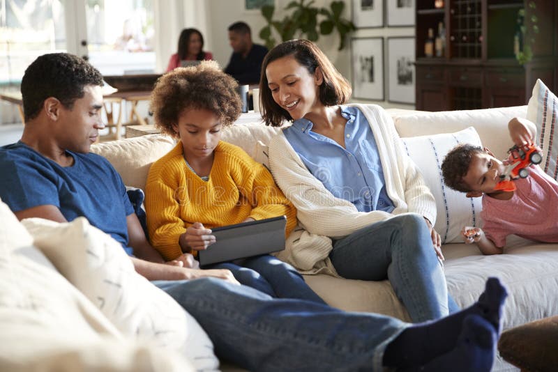 Three generation family family spending time at home in their living room, parents and young kids in the foreground, grandparents in the background, selective focus