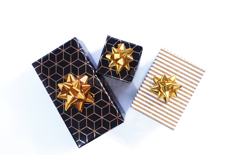 Three gift boxes are black-gold with a geometric pattern and a gold bow and black with a white and gold shiny lid and a gold bow. Isolate on a white background stock images Three gift boxes are black-gold with a geometric pattern and a gold bow and black with a white and gold shiny lid and a gold bow. Isolate on a white background stock images
