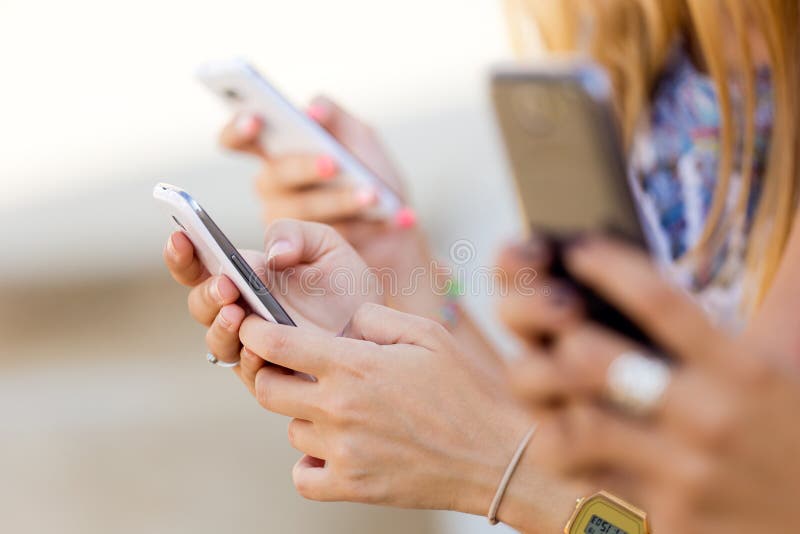 Three girls chatting with their smartphones at the campus