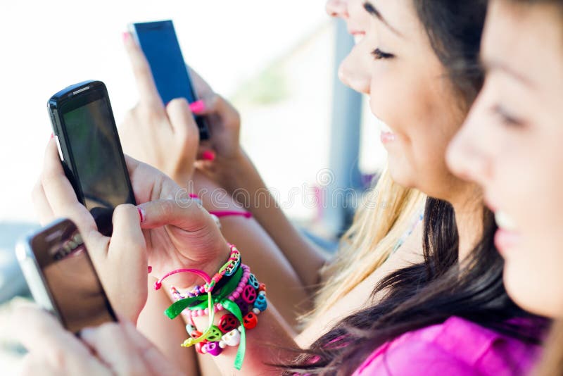 Three girls chatting with their smartphones