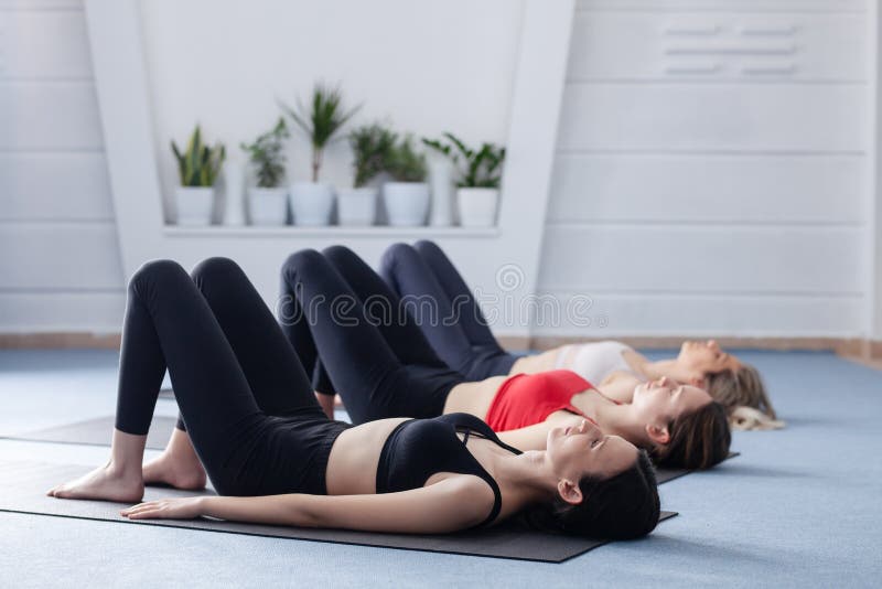 Three girls practicing yoga. Yoga instructor with her students meditating in a studio