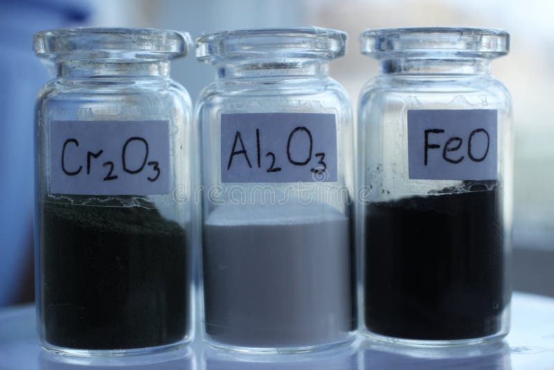 Metal oxides in three glass jars with chemical formulas.