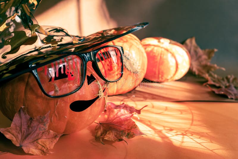 Three halloween pumpkins, one painted as Jack`s lantern in bloody glasses, witch hat, fall leaves, shadows, spiderweb royalty free stock photography
