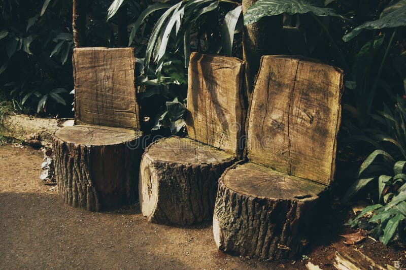 Three handmade wooden stools out of logs in the forest on green background royalty free stock photos
