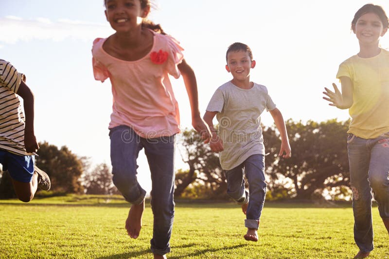 Three happy children running barefoot in a field in Summer stock photo Three happy children running barefoot in a field in Summer stock photo