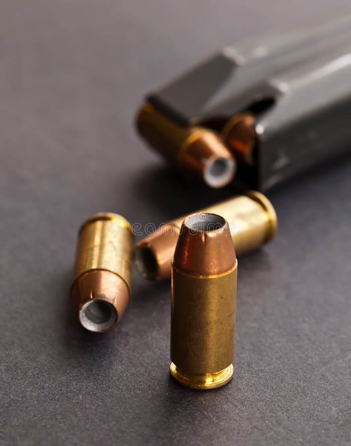 Three hollow point bullets next to a black pistol magazine stock photography