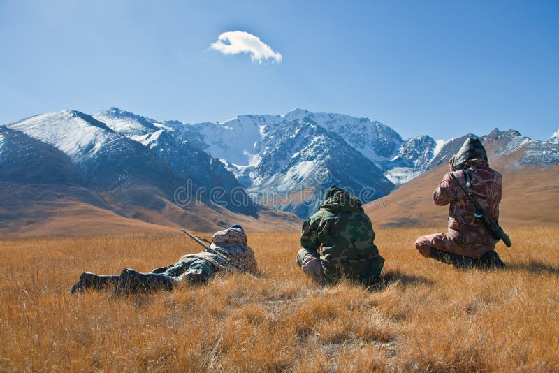 Three hunters looking through binoculars in mountains of Tien Sh