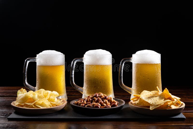 Three Ice-cold Beer Mugs and Plates with Appetizers on Wooden Base on Black Background Stock Image - Image of plates, alcohol: 187924627 Three Ice-cold Beer Mugs and Plates with Appetizers on Wooden Base on Black Background Stock Image - Image of plates, alcohol: 187924627