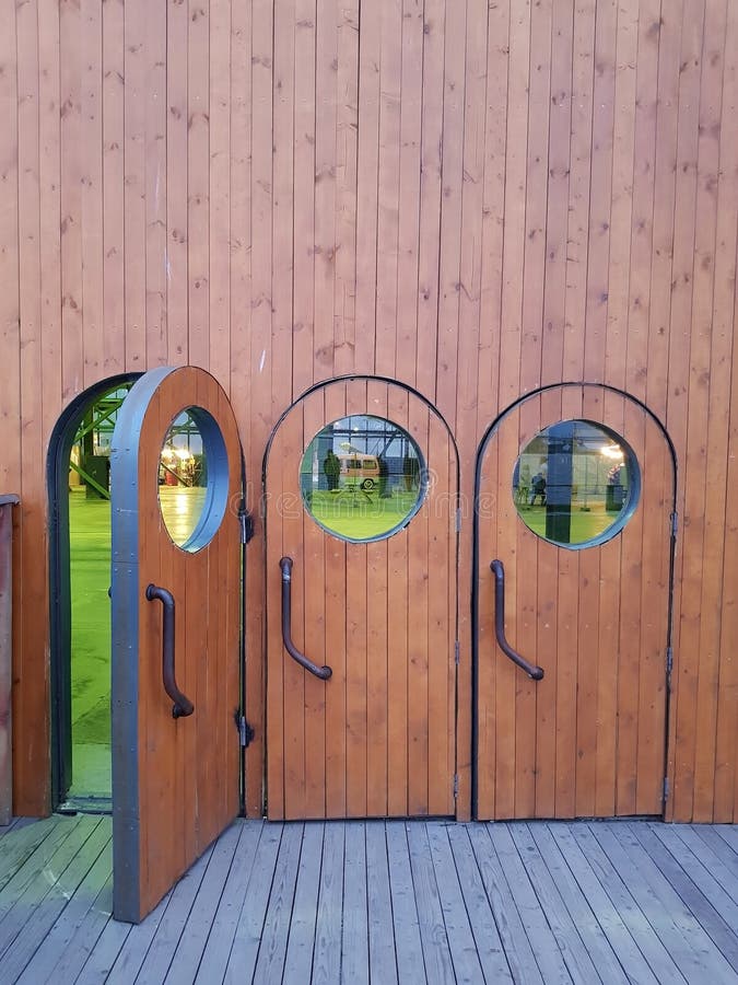 Three Identical, Standing Side By Side, Brown Wooden Doors With Round