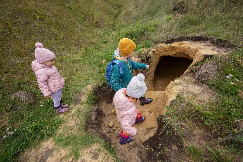 Three Kids Explore Limestone Stone Cave at Mountain Stock Photo Image