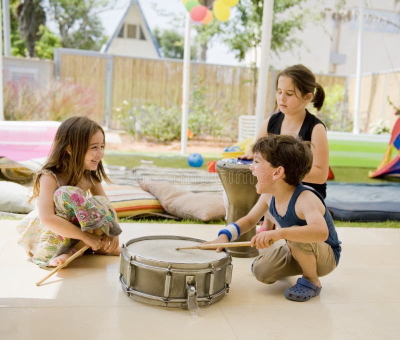 Tri deti vo dvore baví s bubny.