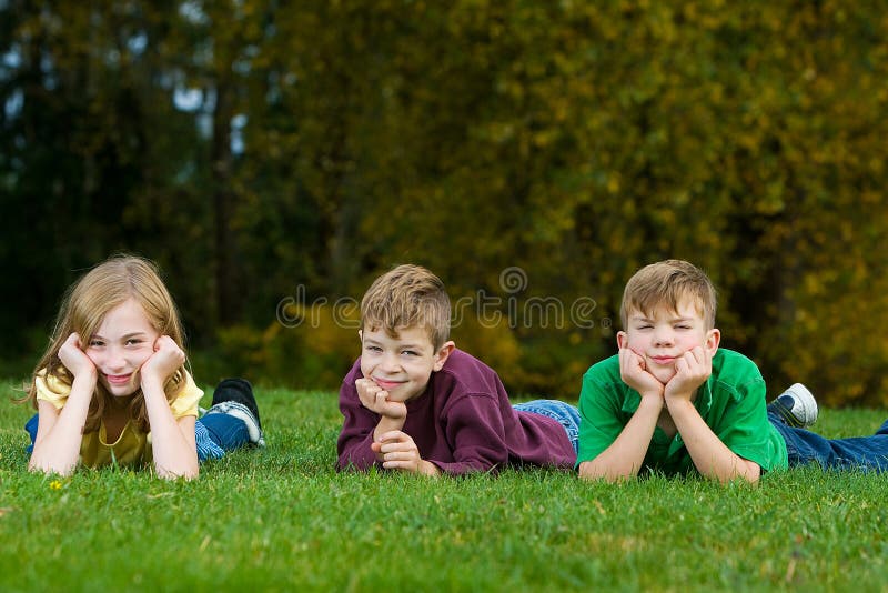 Three kids laying down in the grass