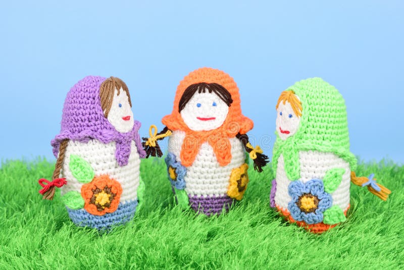 Three Knitted Dolls Stand Opposite Each Other on Green Grass Stock